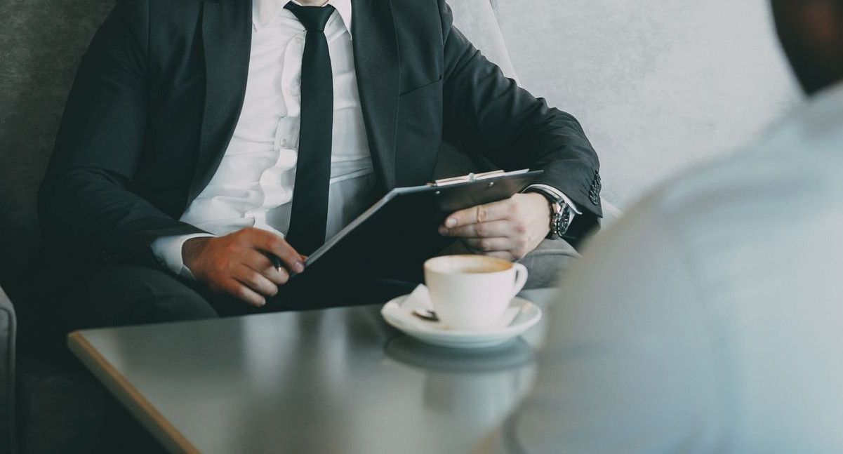 Two businessmen having a serious conversation over coffee in a stylish cafe setting.